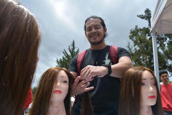 Estudiante de la Universidad Nacional participando en la actividad de peinados de la Escuela A Cuidar Se Aprende